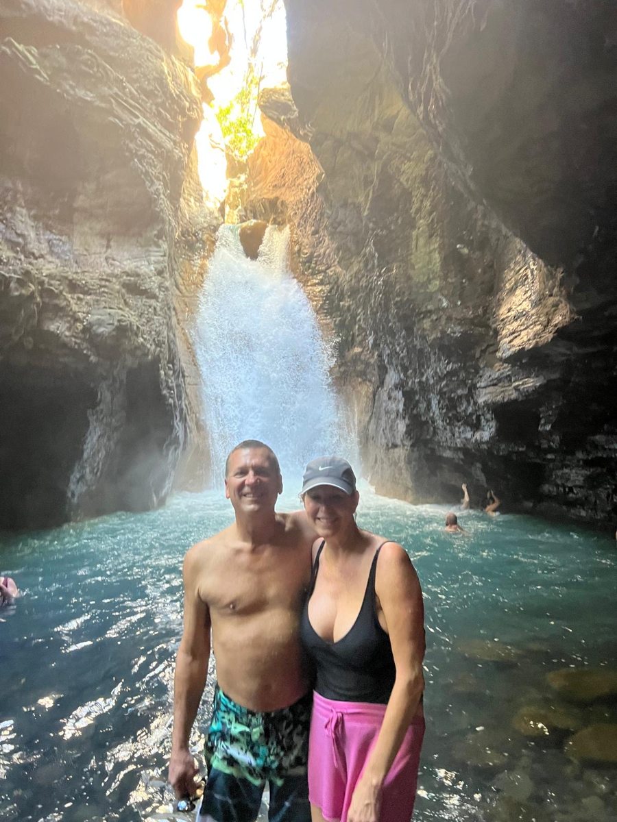 A couple smiling in a waterfall pool