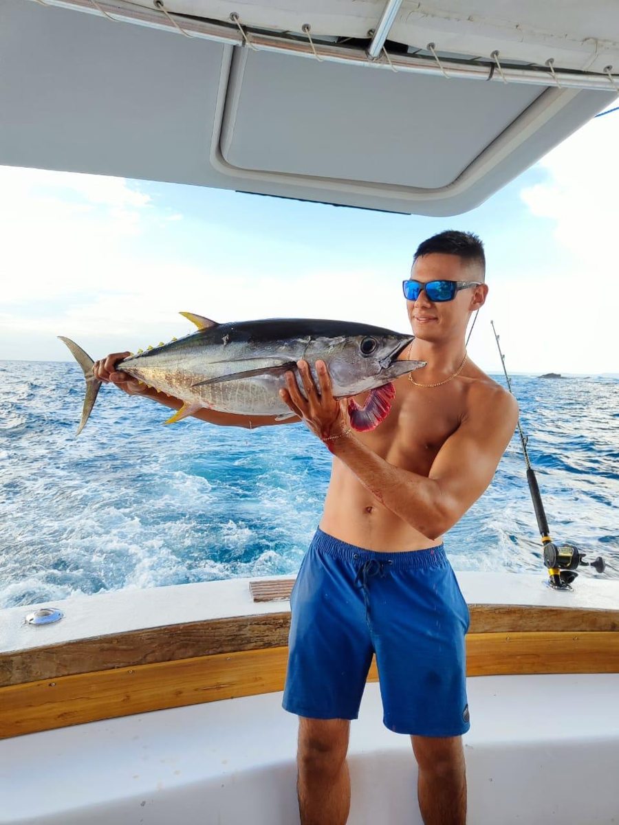 A guest holding a fish on a boat