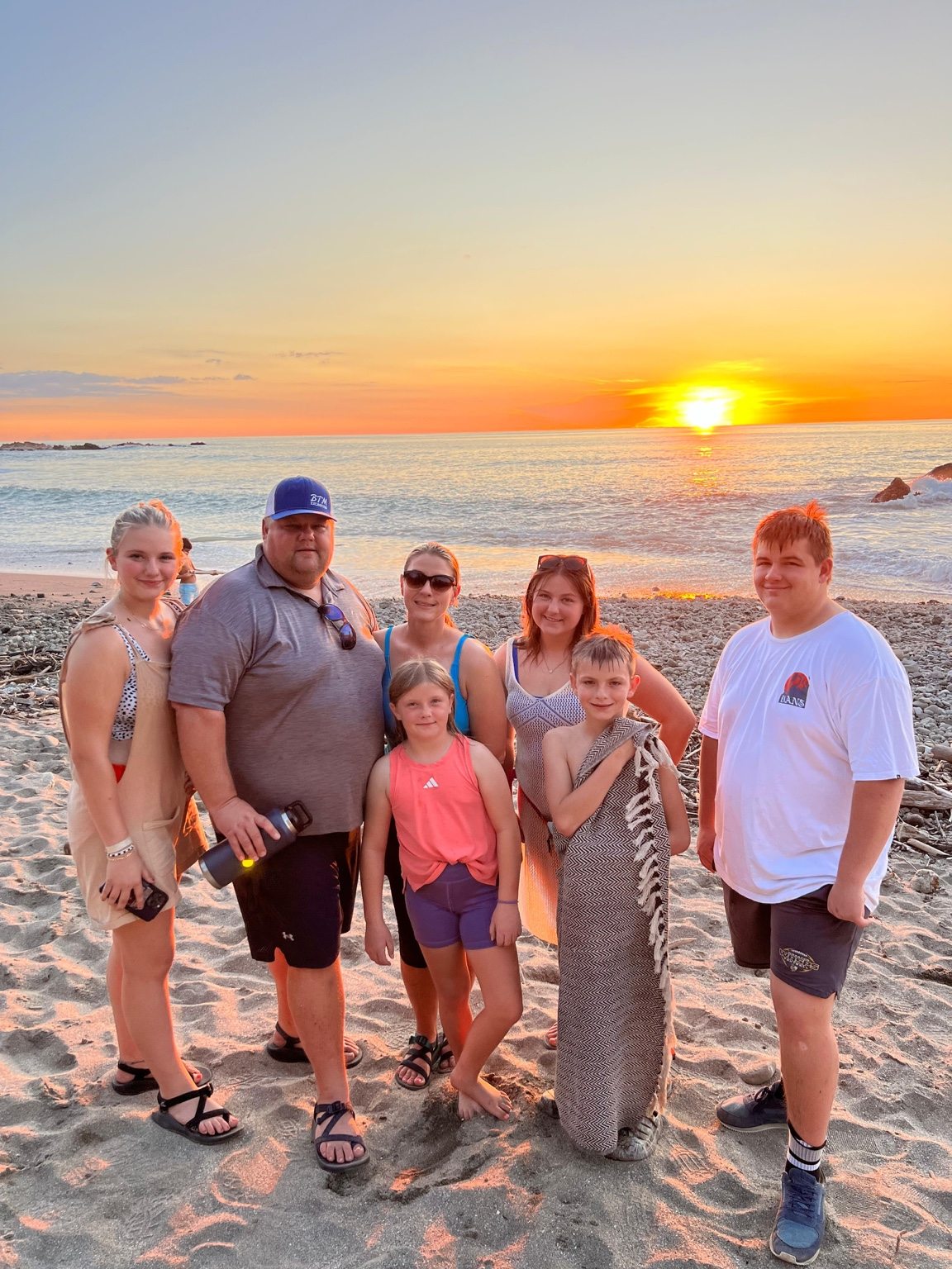 Family together on a Pacific beach at sunset