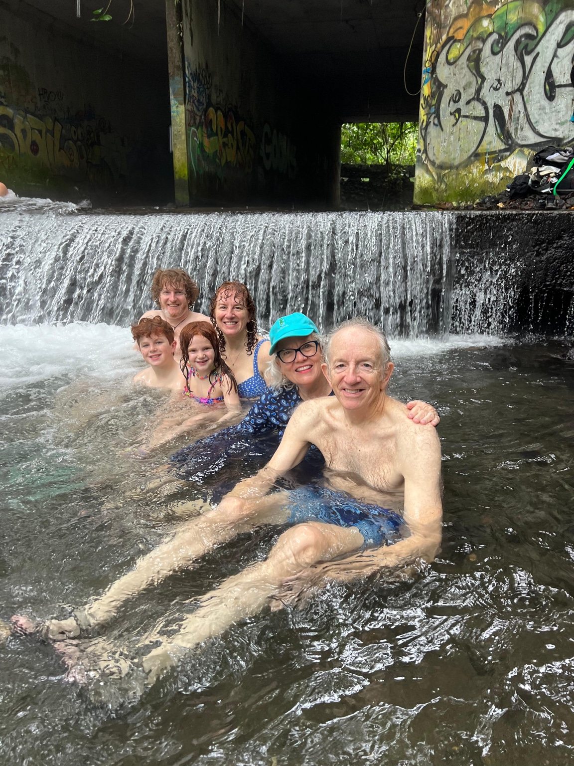 Children and family playing together in a waterfall pool