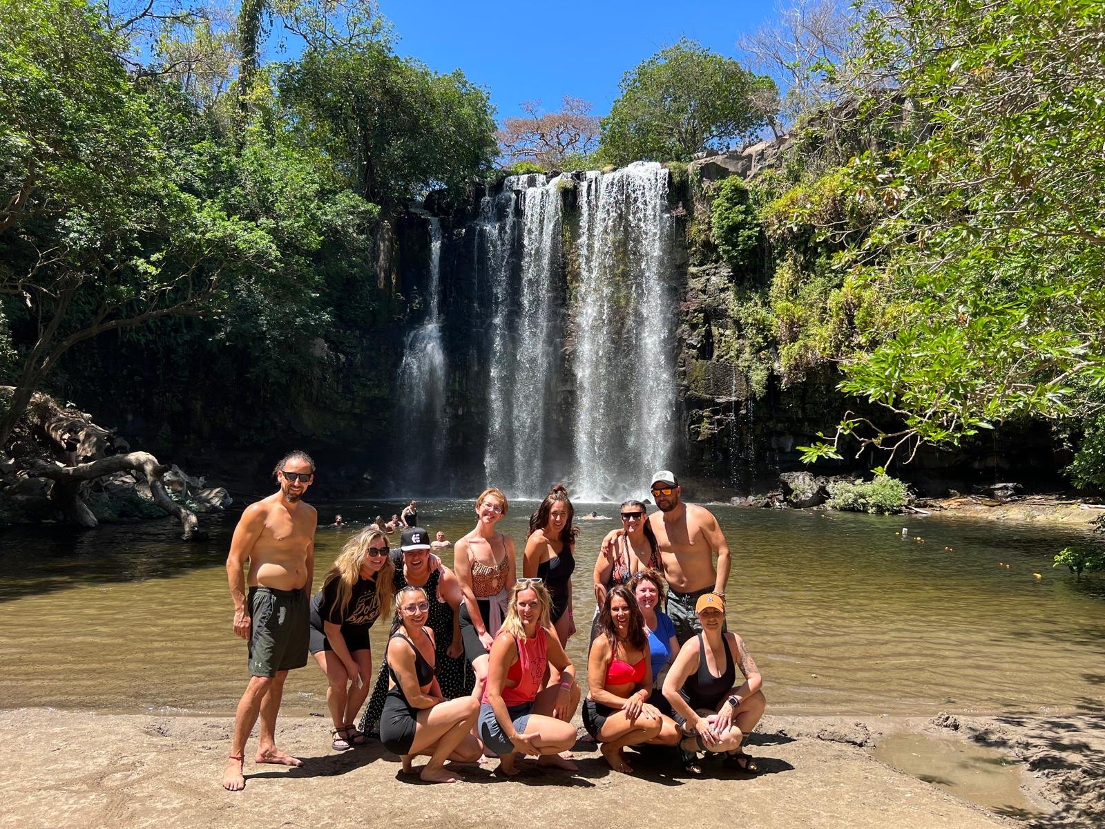 Friends and children smiling together at a waterfall